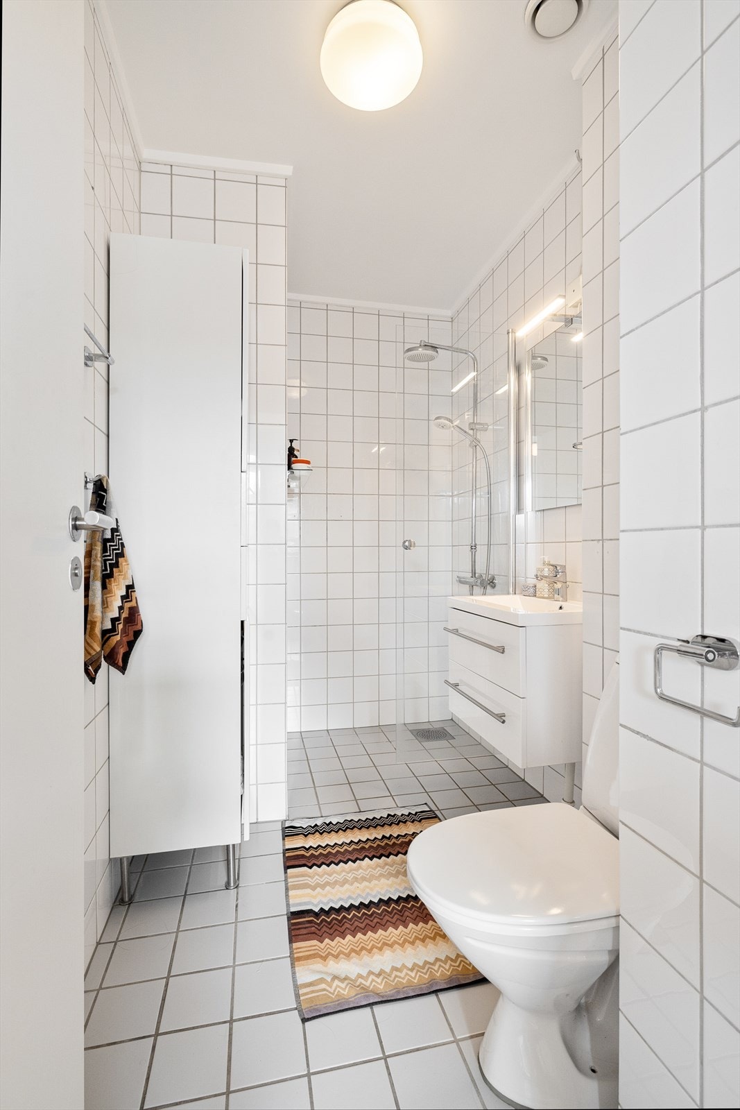 Tidløst og romslig bad med flislagte overflater og gulvvarme. Galleribilde