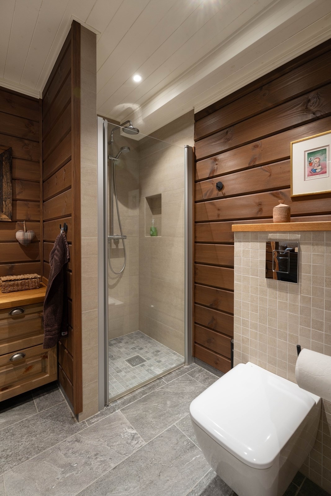 Bad/wc med dusjnisje. Flott kombinasjon av trepanel og fliser som skaper en varm og innbydende atmosfære. Galleribilde