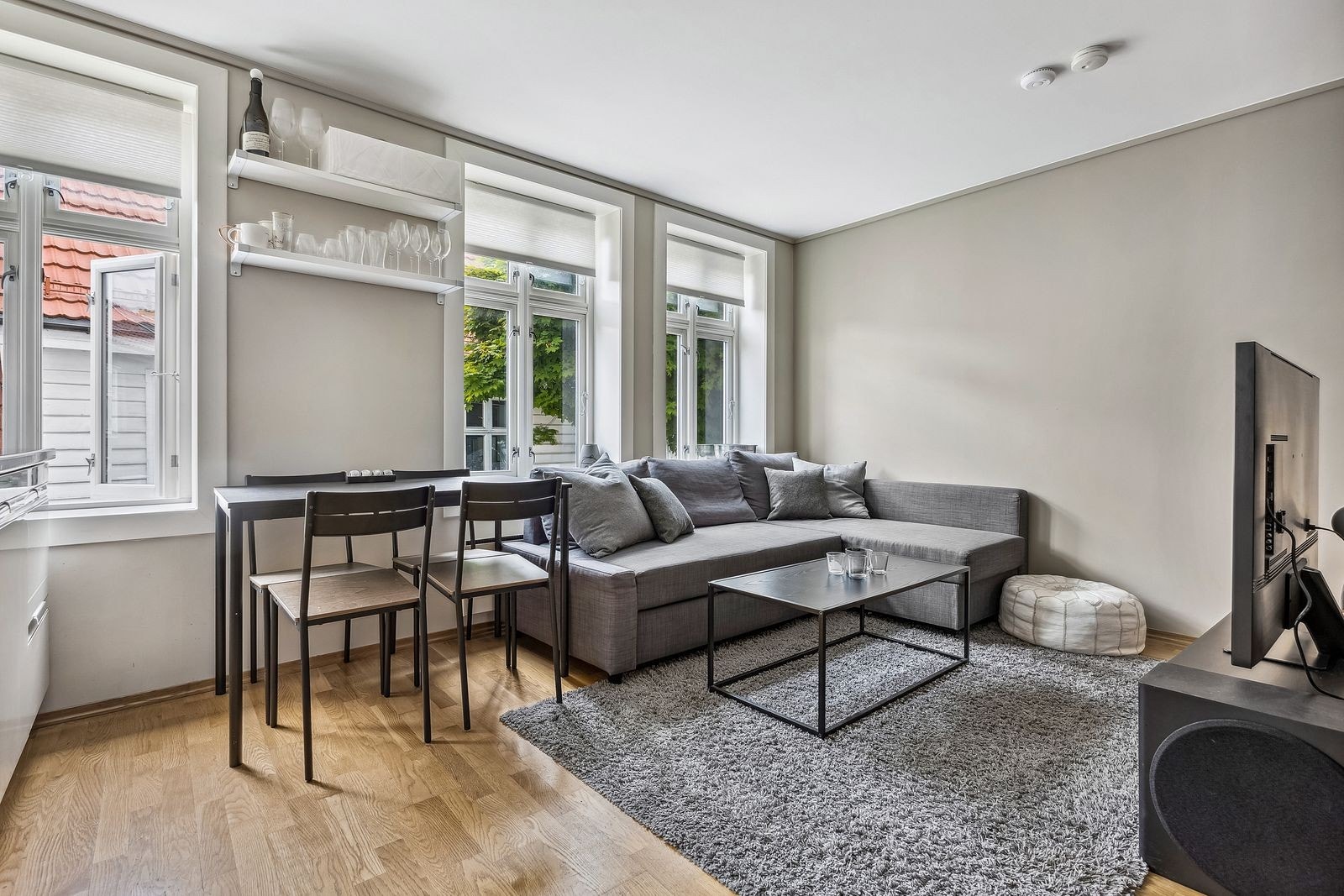Lys og fin stue med god takhøyde. Stuen er innredet med sofa, kjøkkenbord og stoler. Galleribilde