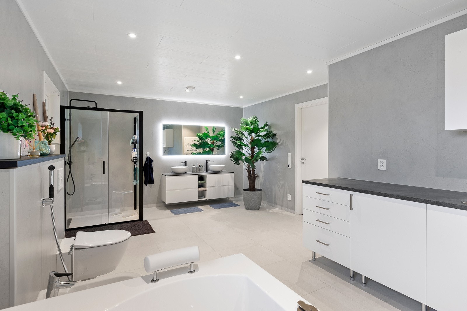 Stort og romslig bad/vaskerom med spotter i tak og behagelig varme i gulv. Vaskemaskin og tørketrommel plassert i innredning med god lagringsplass. Galleribilde