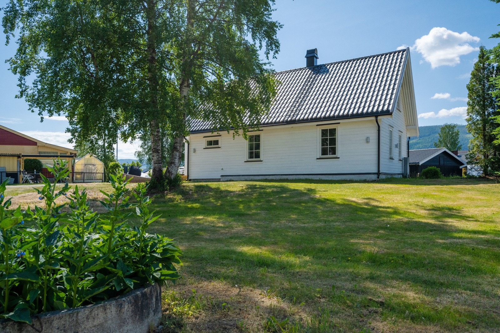 Romslig tomt på - opparbeidet med plen og hage. Vei over tunet til eiendom bakenfor. Galleribilde