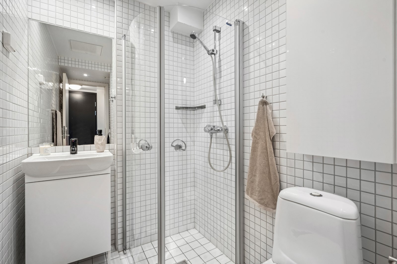 Badet er bestående av servant med underskap, innfliset speil, gulvmontert klosett, dusjhjørne med svingbare glassdører. Galleribilde