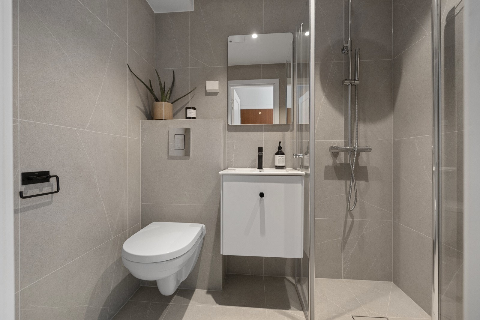 Delikat, flislagt baderom fra 2023. Det er opplegg for vaskemaskin på badet. Galleribilde