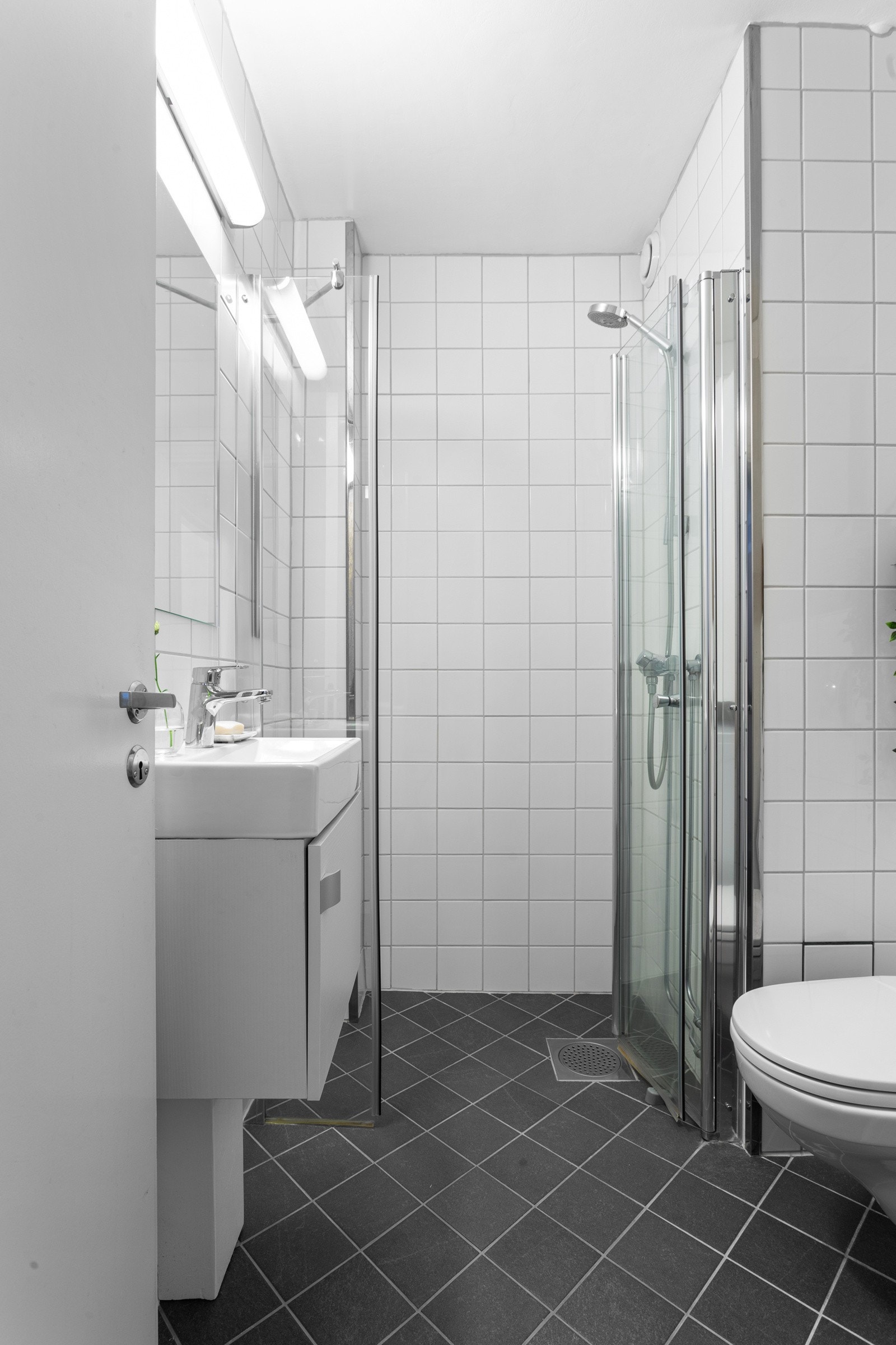 Badet er innredet med vegghengt toalett, dusjhjørne med svingbare dører, servant med underskap (nytt 2024) og speil. Galleribilde