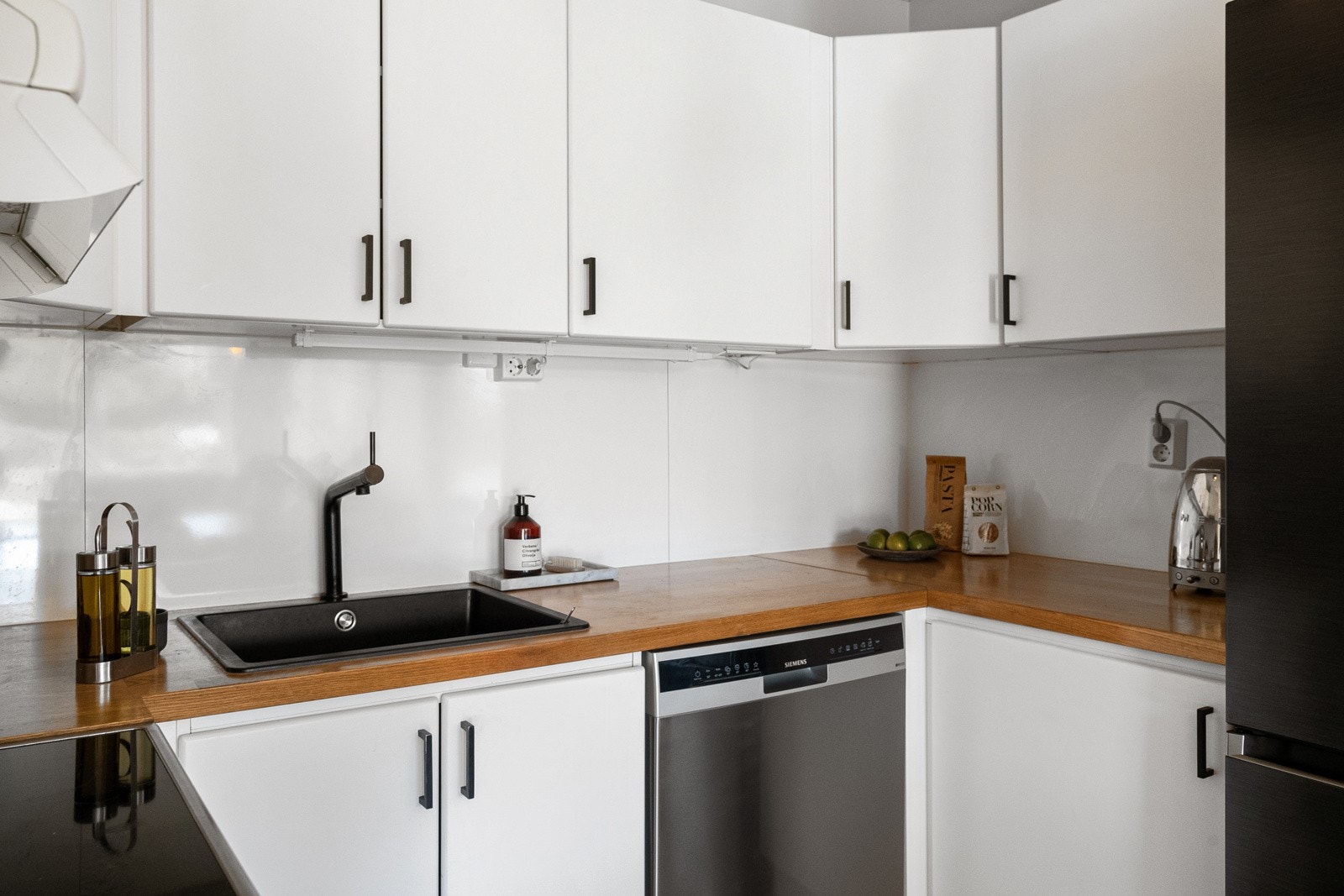 Kjøkkeninnredning med glatte fronter, heltre benkeplate(2021), ventilator til fellesanlegg, kompositt oppvaskkum(2021), blandebatteri(2021), kitchenboard over benk og opplegg til oppvaskmaskin. Galleribilde