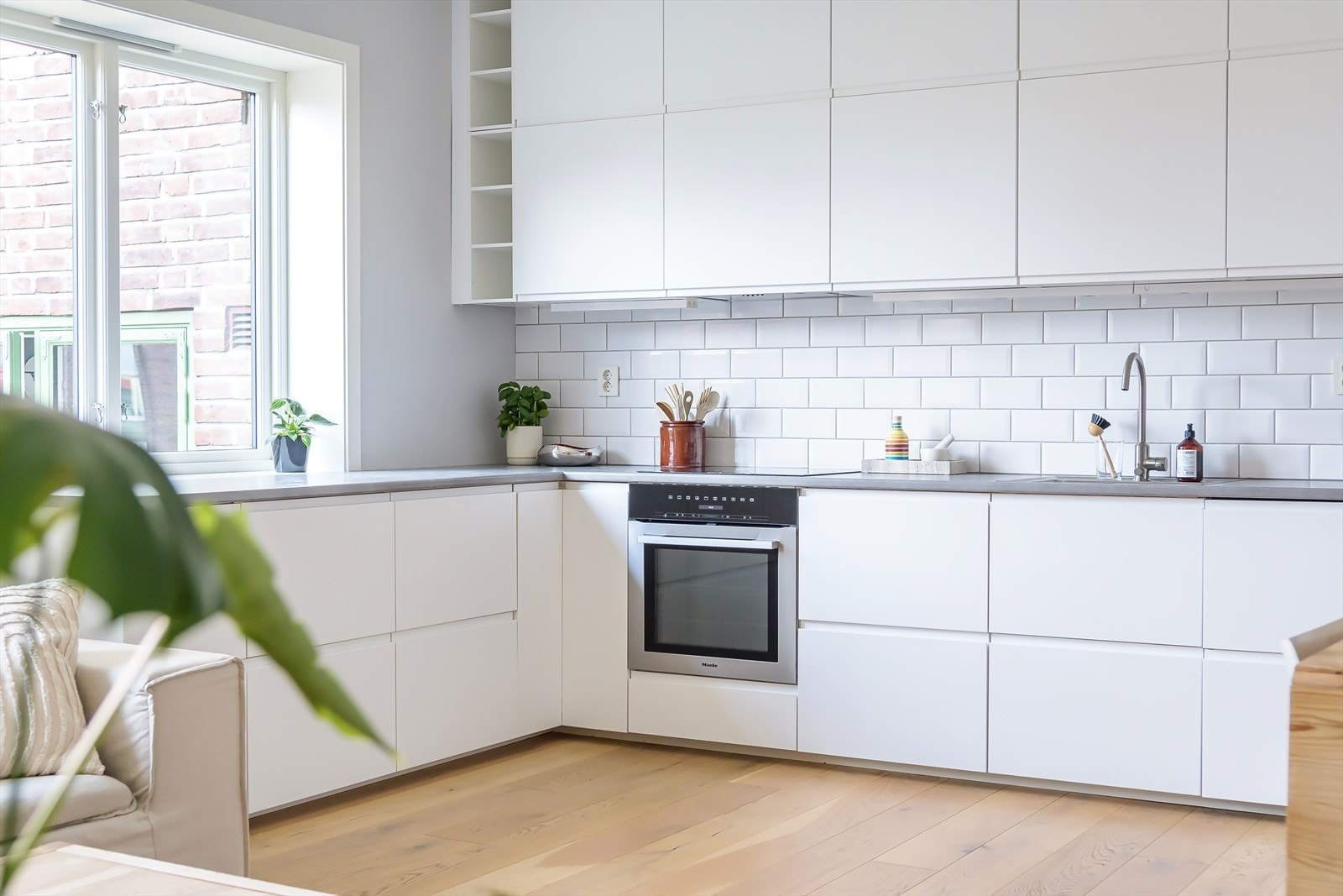 Stilrent IKEA-kjøkken fra 2015 med hvite fronter, fliser på bakvegg og laminert benkeplate. Galleribilde