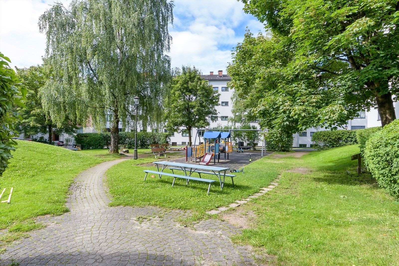 Hyggelig og grønne fellesområdet med sittegruppe og lekeplass. Galleribilde