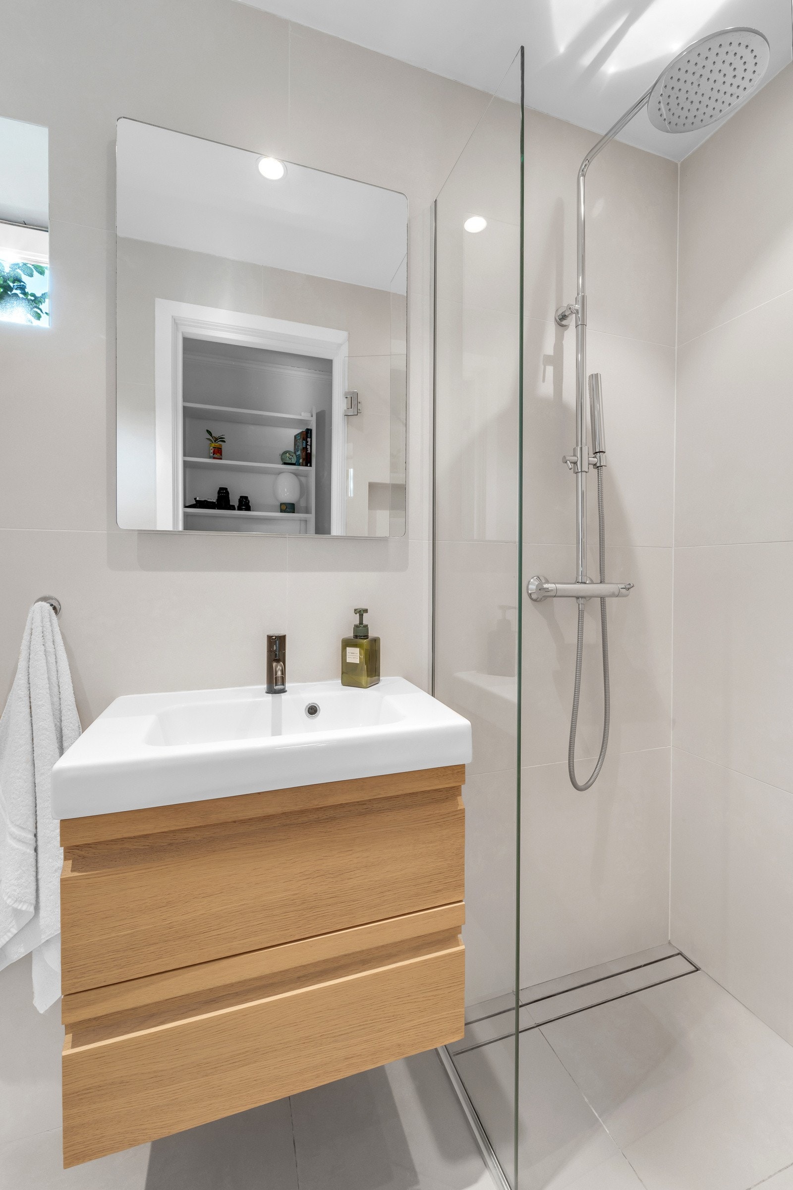 Baderommet inneholder servant med underskap, speil med belysning, vegghengt toalett og dusj. Galleribilde