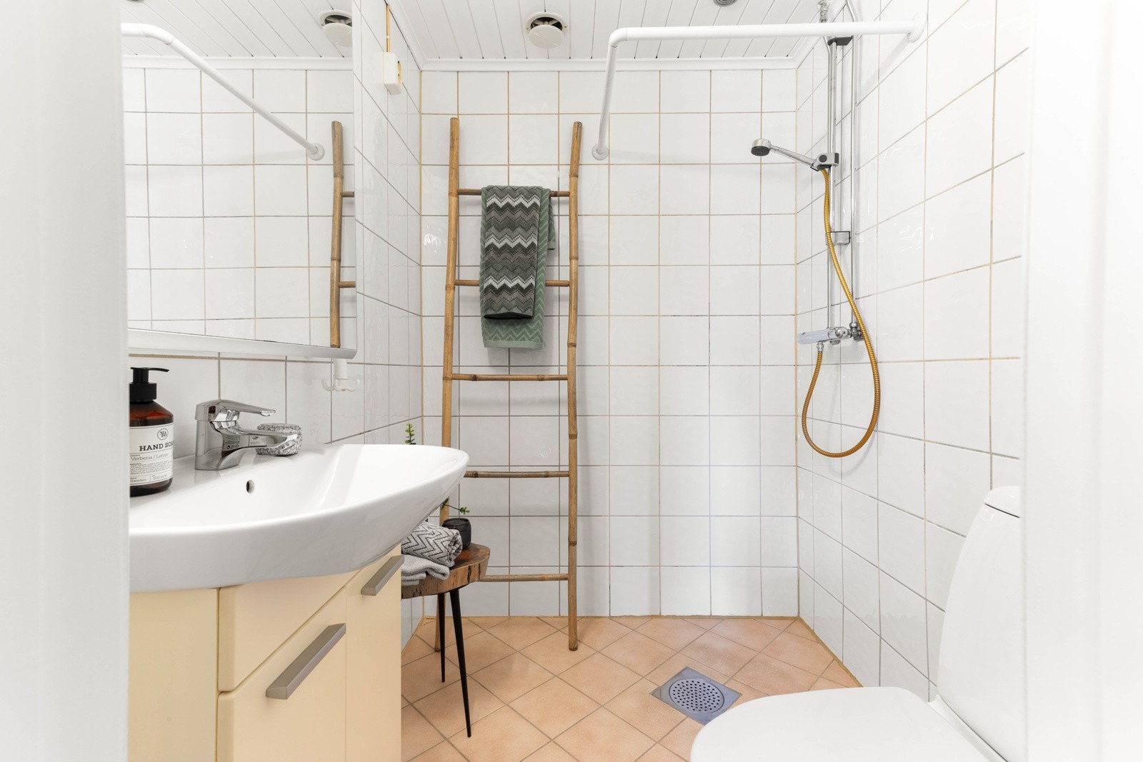 Flislagt bad som inneholder dusj på gulv, servant og gulvstående klosett. Galleribilde