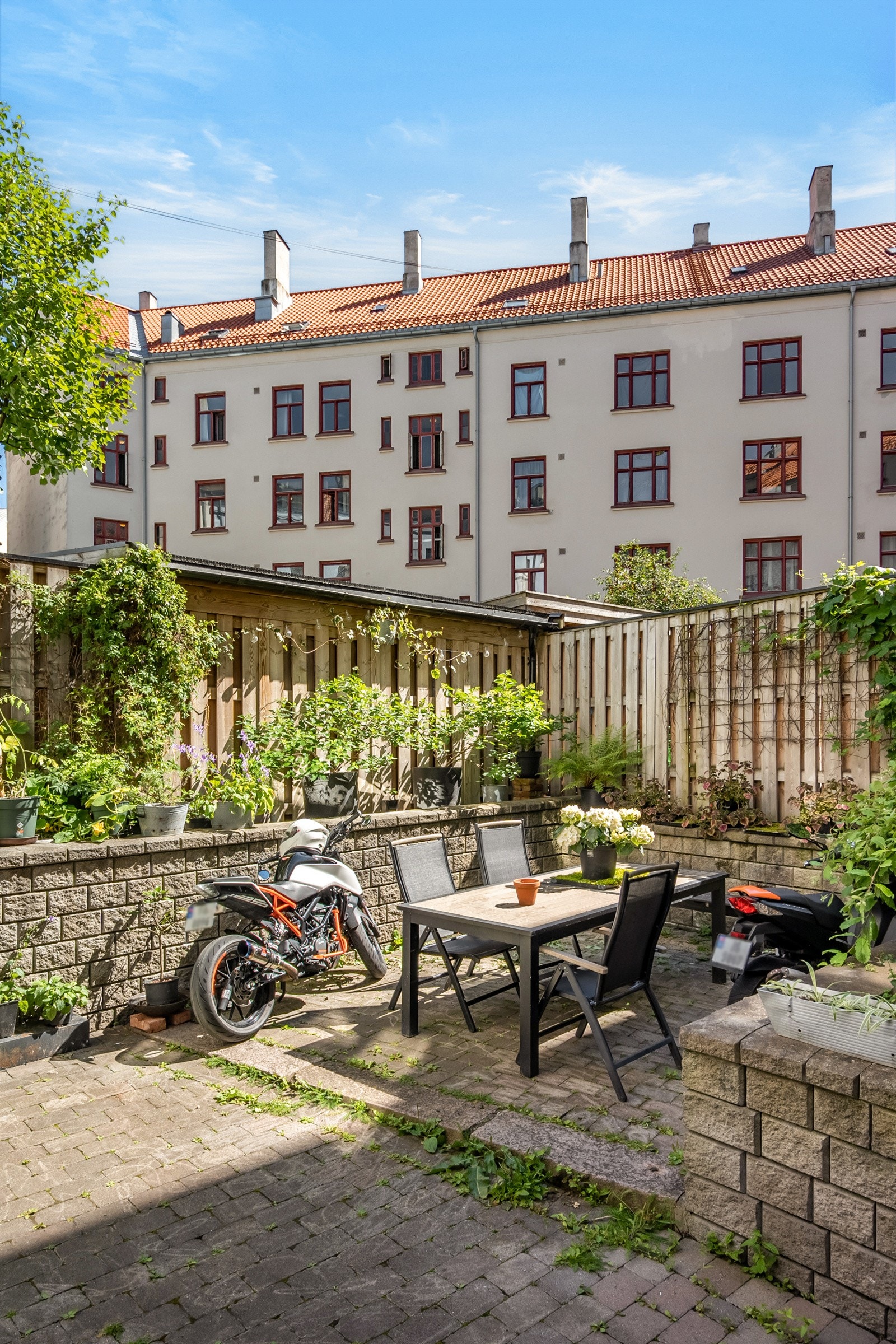 Bakgården er utstyrt med sittegruppe og velholdte grøntområder, samt sykkelparkering og drivhus for planter som kan benyttes av beboerne. Galleribilde