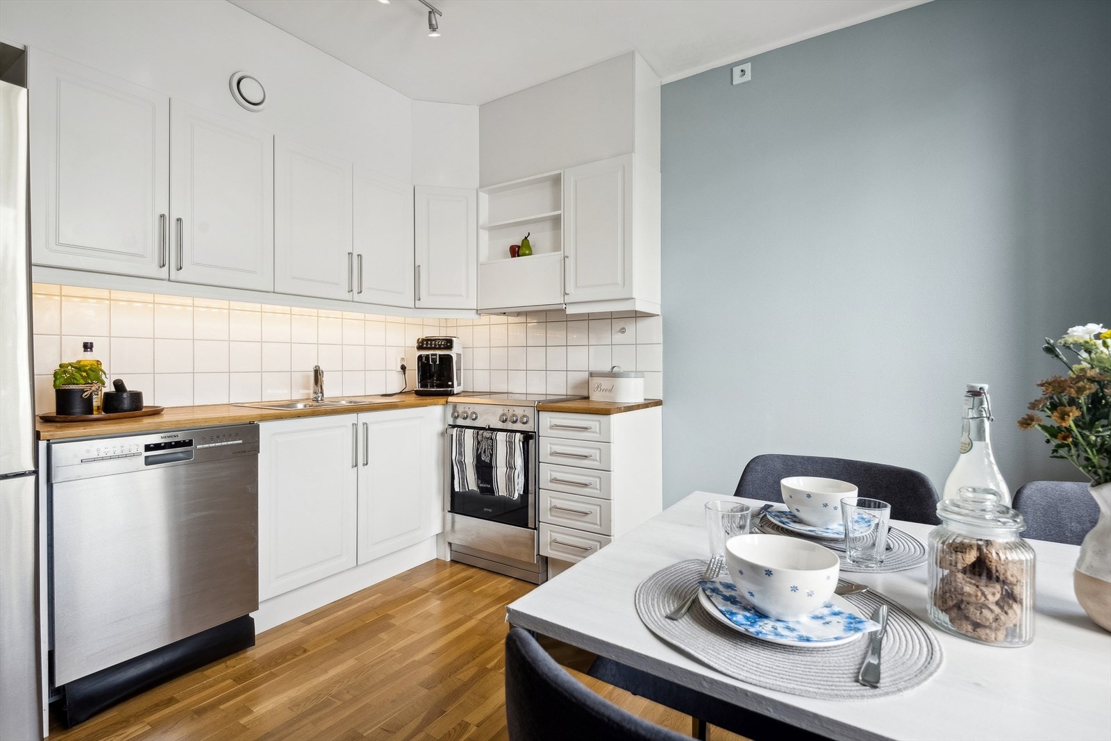 Stue/kjøkken i åpen løsning, kjøkkeninnredning med hvite profilerte fronter. Benkeplate av laminat. Galleribilde