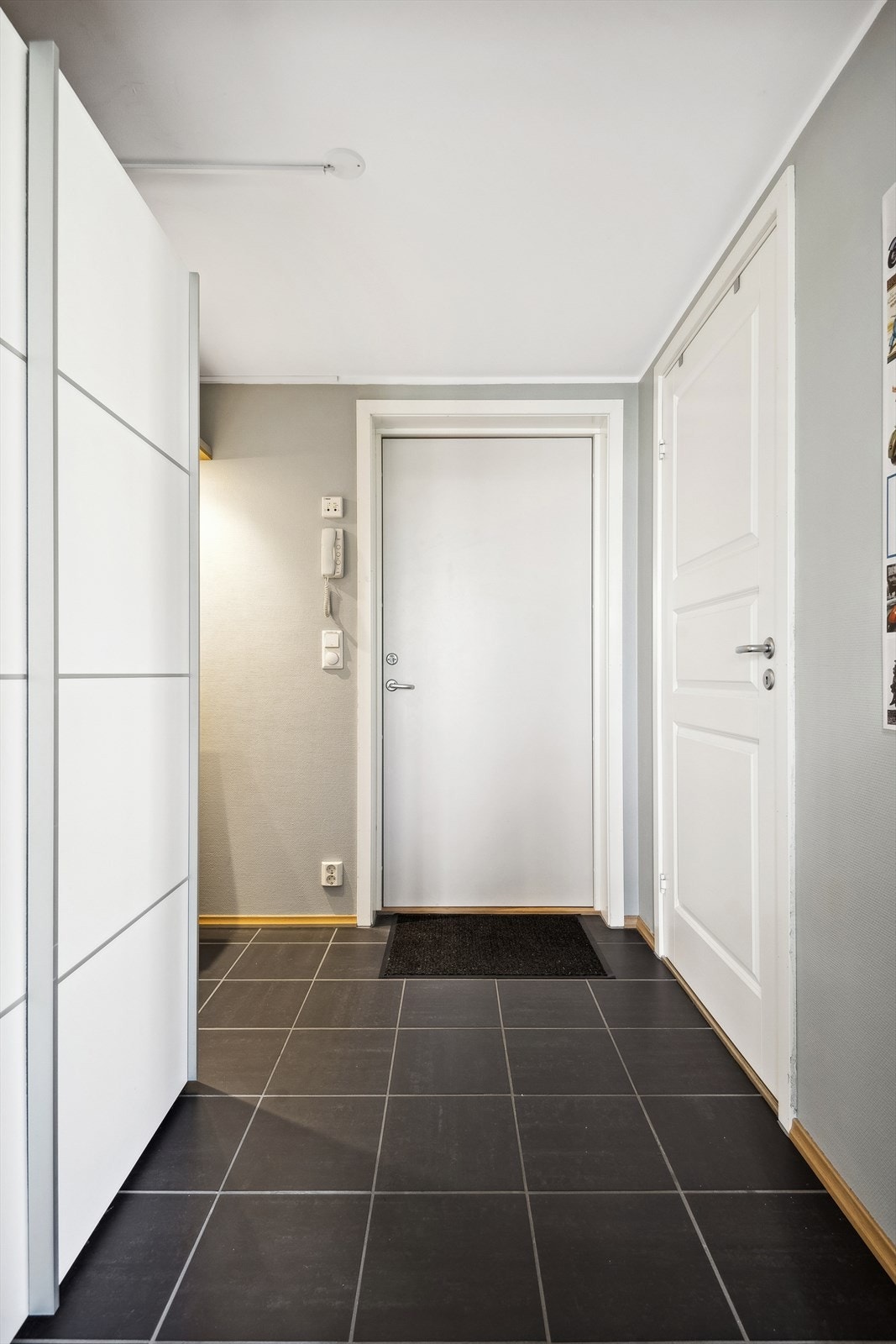 Moderne entrè med flislagt gulv og romslig garderobeskap for yttertøy. Galleribilde