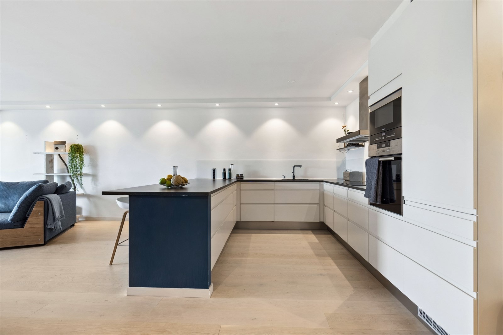 Moderne kjøkkeninnredning med hvite glatte fronter, laminat benkeplate, oppvaskkum i kompositt og glassplate over benk. God benke- og lagringsplass. Galleribilde