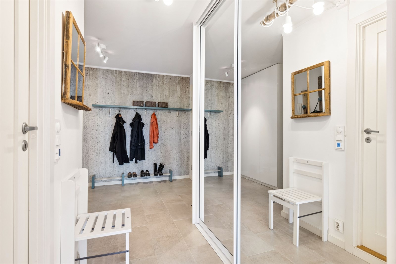 Romslig og innbydende entré med flislagt gulv og skyvedørsgarderobe med speilfronter. Galleribilde