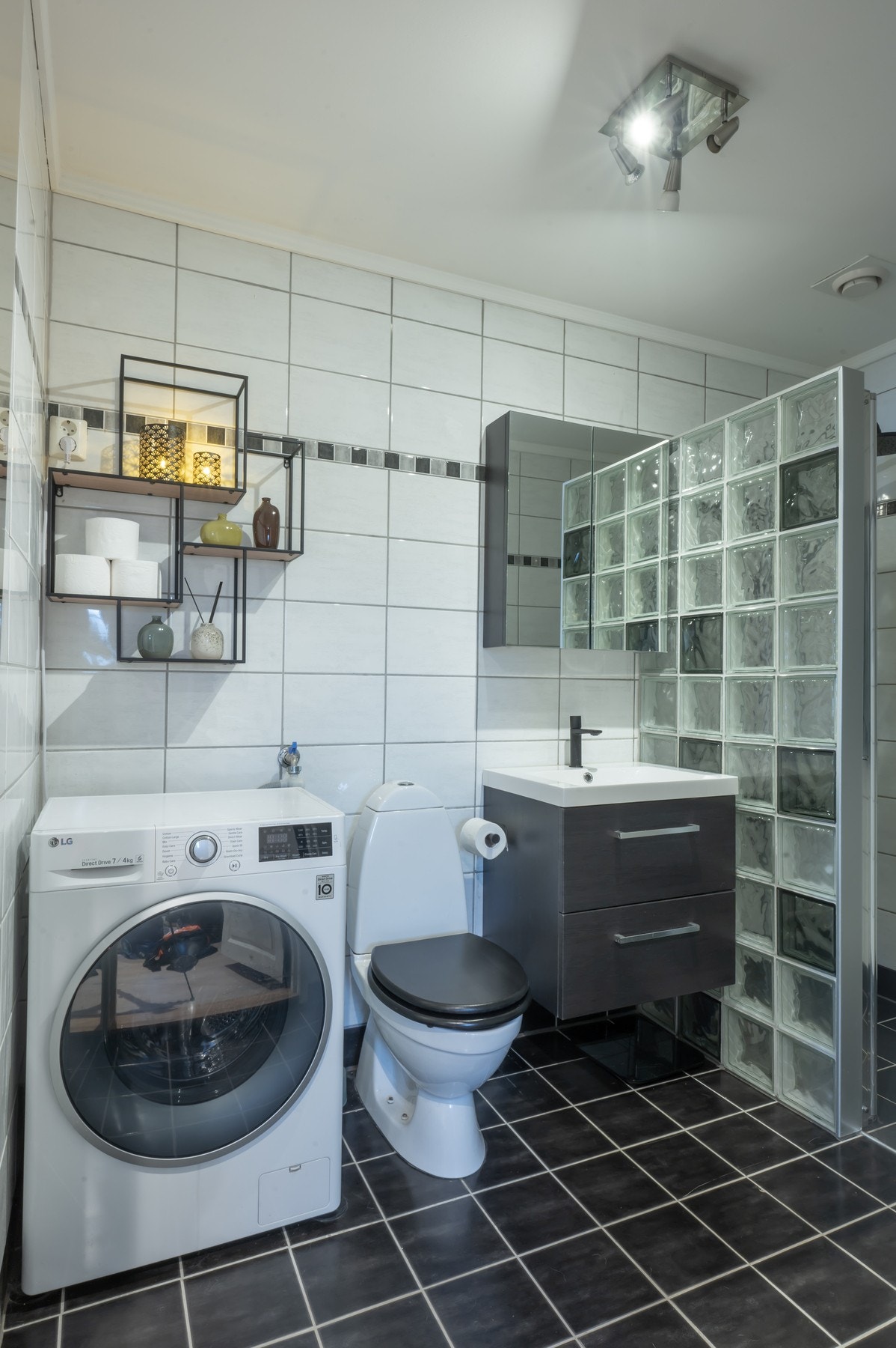 Badet er utstyrt med dusjnisje, opplegg for vaskemaskin, servant, servantskap og wc. Galleribilde