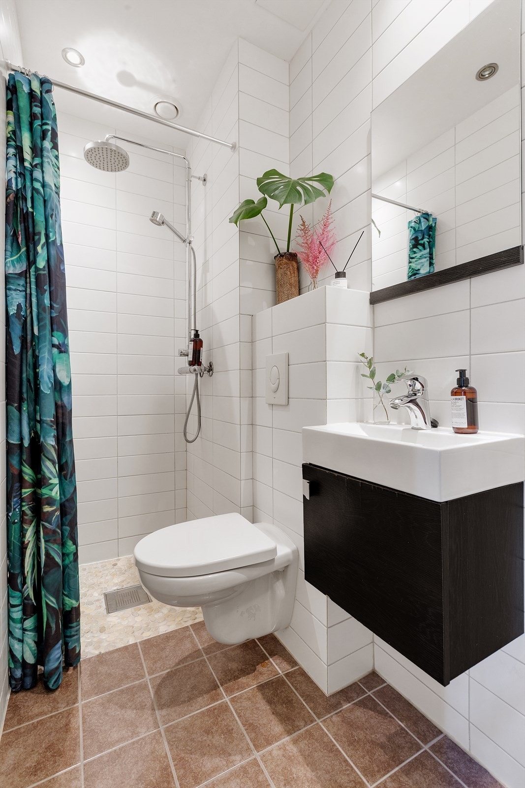 Baderommet er flislagt og har innredning med nedfelt servant, veggmontert toalett og dusj. Galleribilde