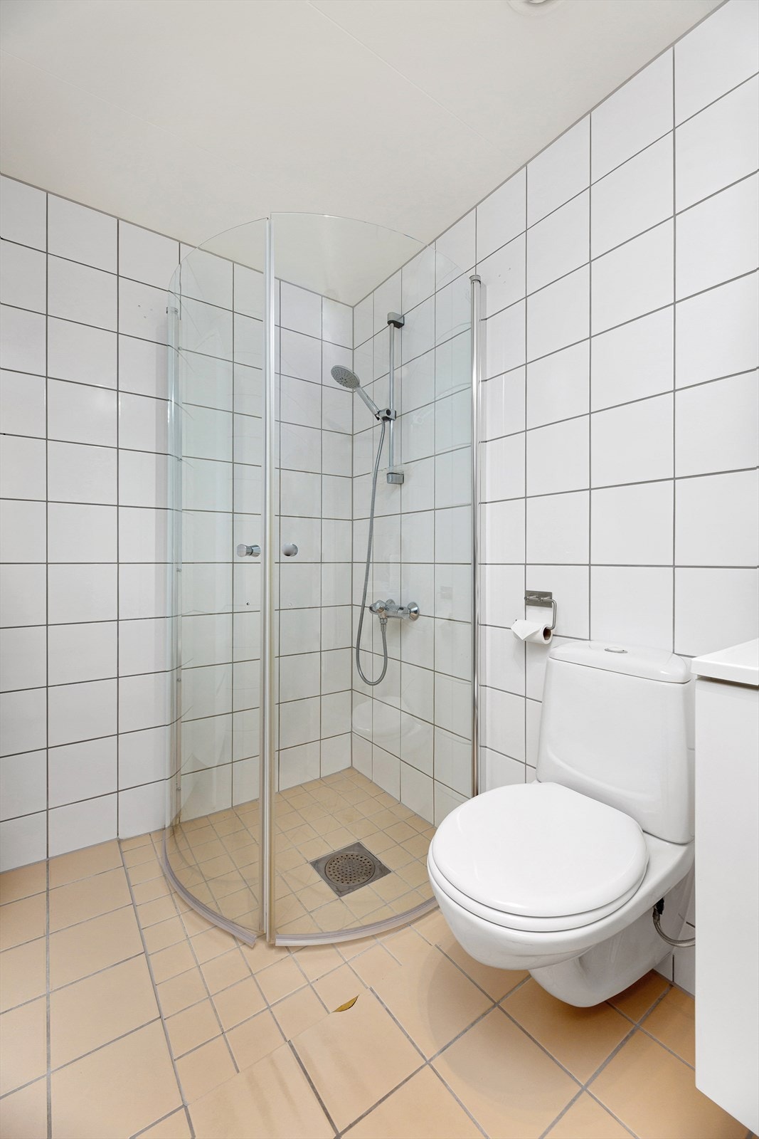 Badet er innredet med vegghengt klosett, servant nedfelt i innrednig og dusjhjørne med svingbare glassdører. Galleribilde