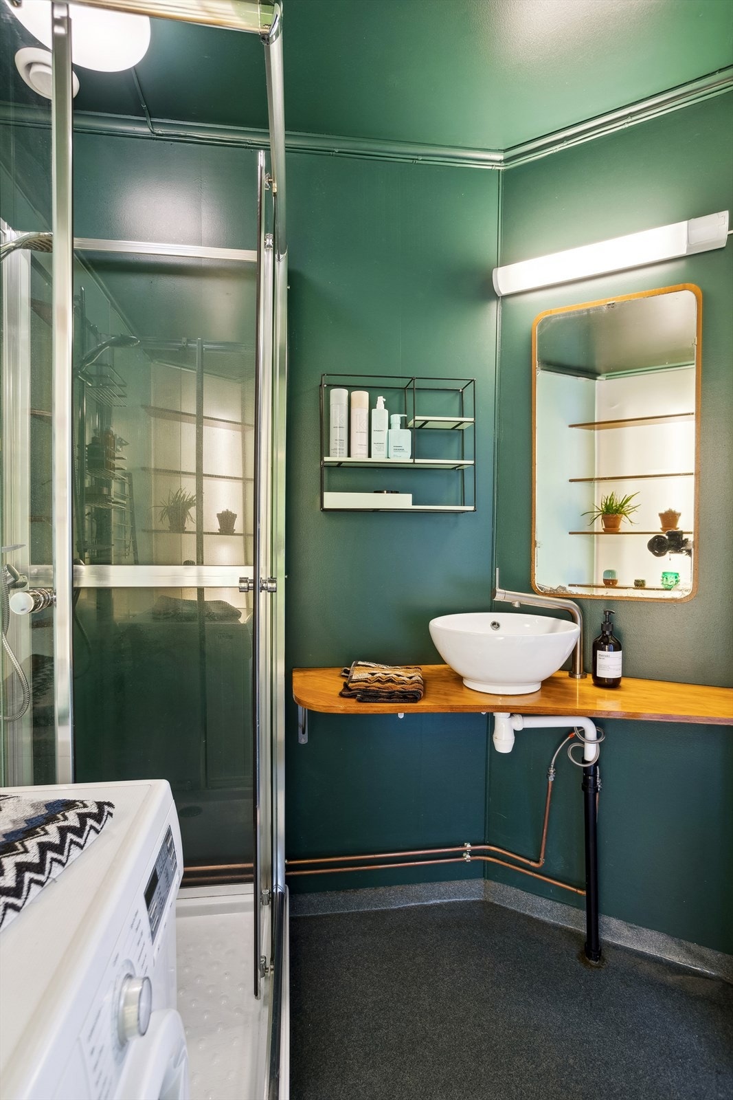 Baderommet er innredet med gulvstående klosett, et dusjkabinett og servant på en vegghengt benkeplate. Galleribilde