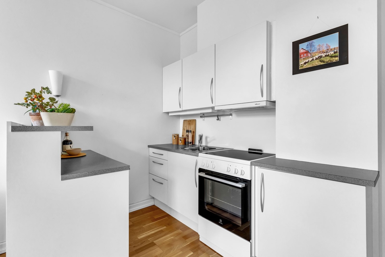 Kjøkkeninnredning med lyse fronter og laminat benkeplate. Belysning under overskap. Galleribilde