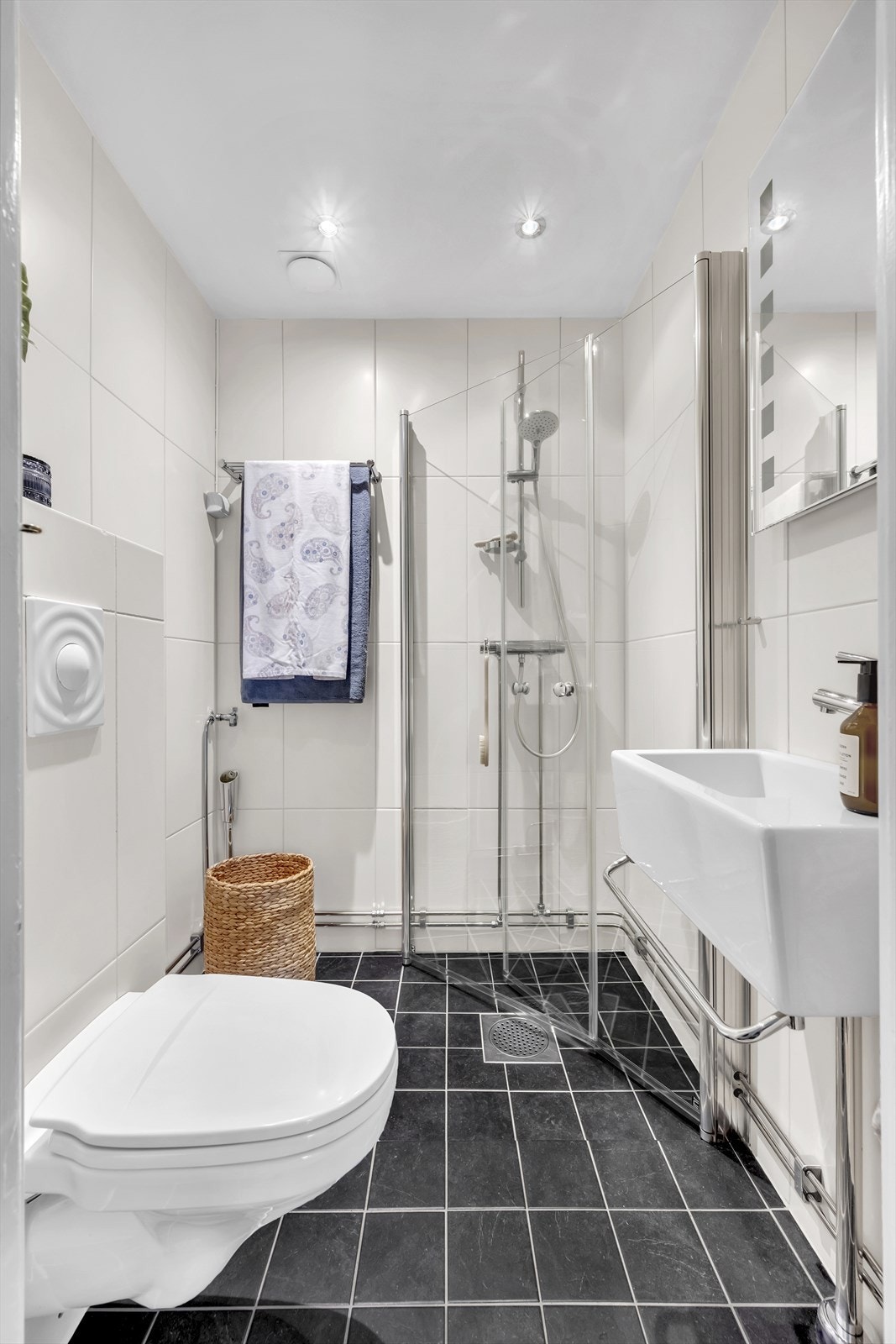 Baderommet er flislagt og har elektrisk gulvvarme. Det er innredet med vegghengt klosett, servant med innredning, speil m/lys og dusjhjørne med svingbare glassdører. Videre er det opplegg for vaskemaskin og badet har naturlig avtrekk. Galleribilde