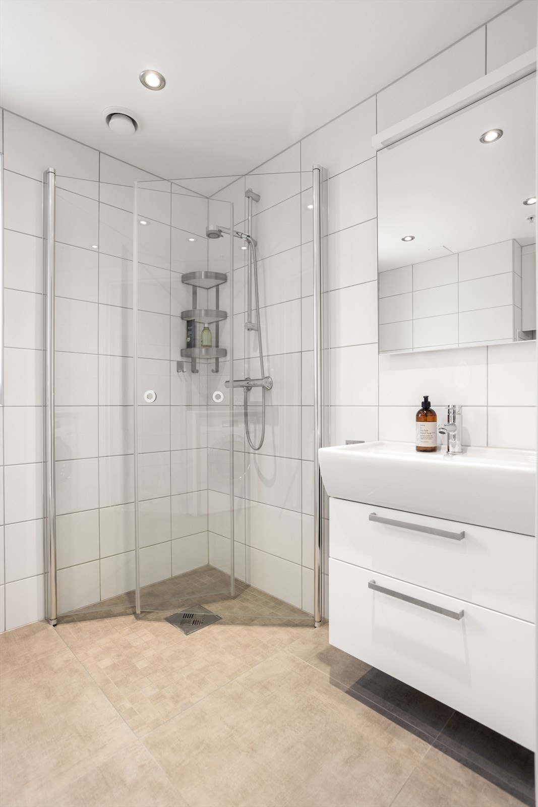 Pent flislagt baderom med dusjnisje i hjørnet samt servant med speilskap. Galleribilde