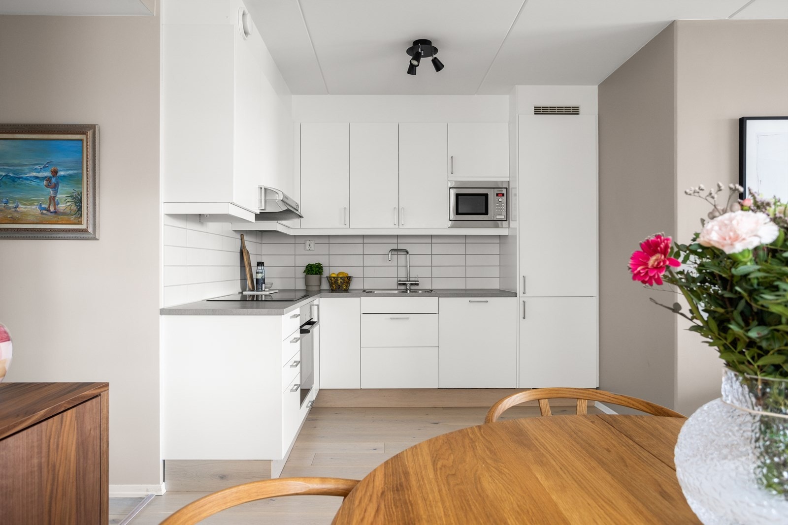 Pent og moderne kjøkken med hvite skap og integrerte hvitevarer. Galleribilde