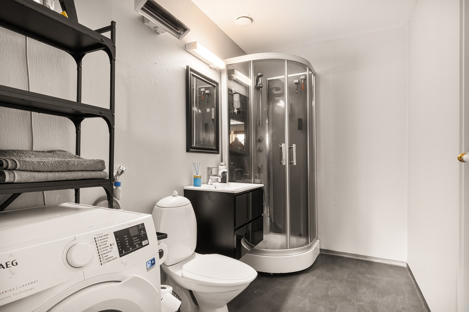 Badet har belegg på gulv, malte plater på veggene og er utstyrt med dusjkabinett, wc, baderomsinnredning og opplegg for vaskemaskin Galleribilde