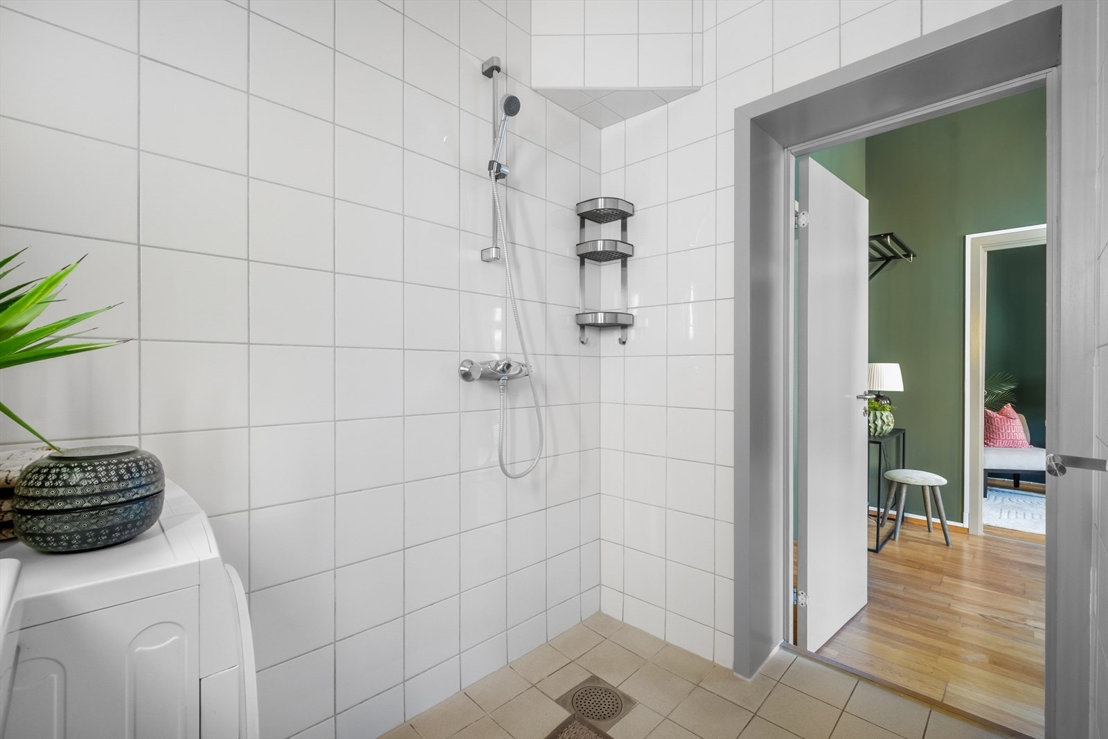 Badet inneholder veggmontert toalett, dusjhjørne, servantskap med overmontert servant, veggmontert speil på vegg med innfelt lys. Galleribilde