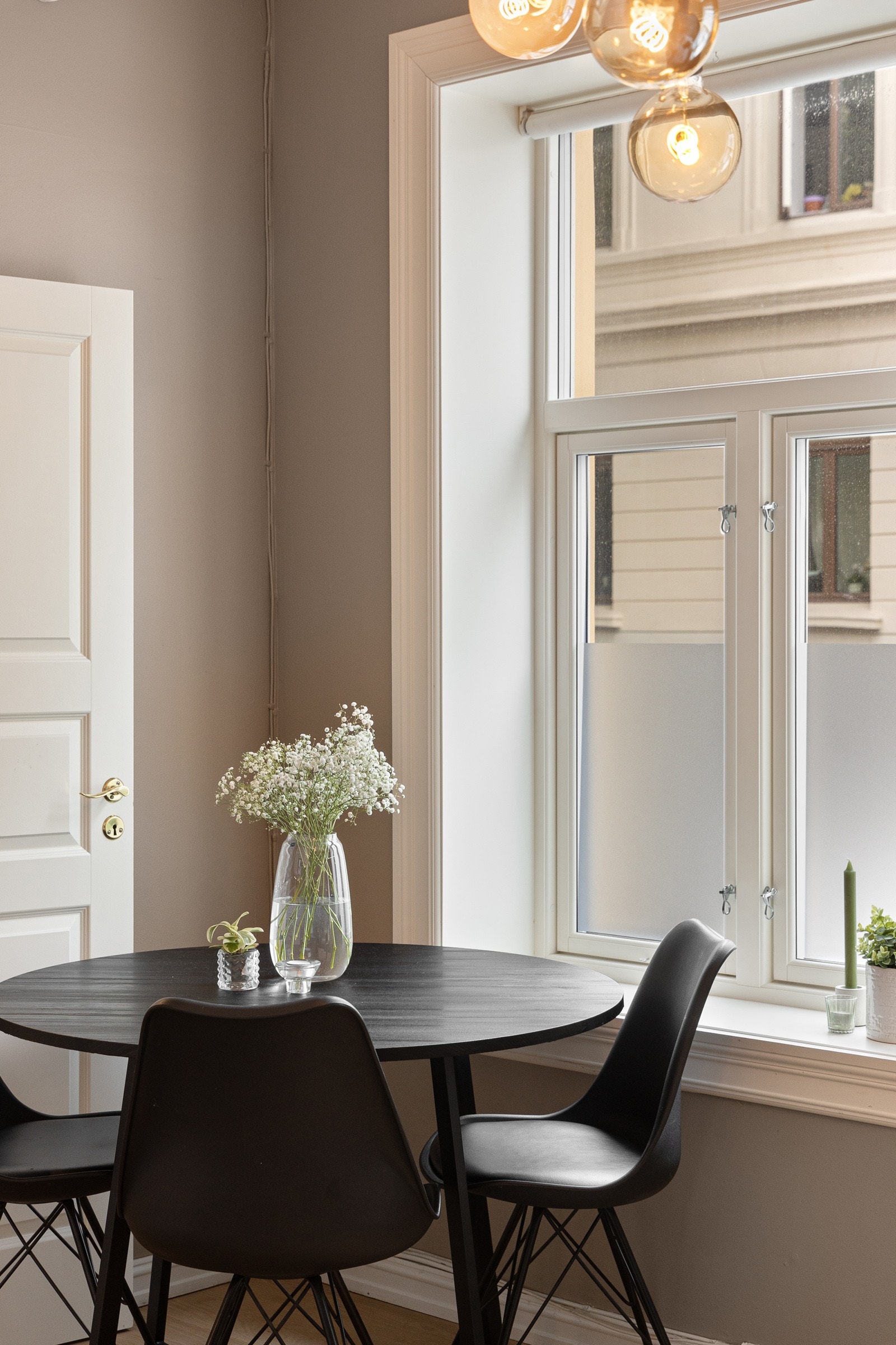 Plass til spisebord ved kjøkkenet. Vinduene har frostet nedre del som skjermer for innsyn, men likevel slipper lys inn. Galleribilde