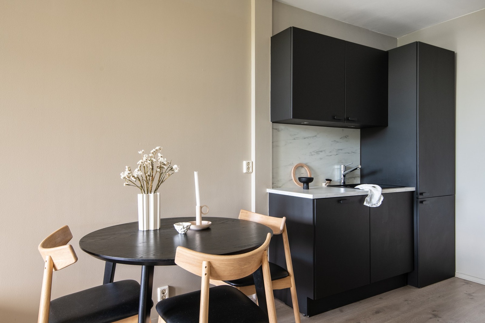 Innredningen har en mørk, glatt utførelse med laminat benkeplate og plate på vegg over benken. Galleribilde