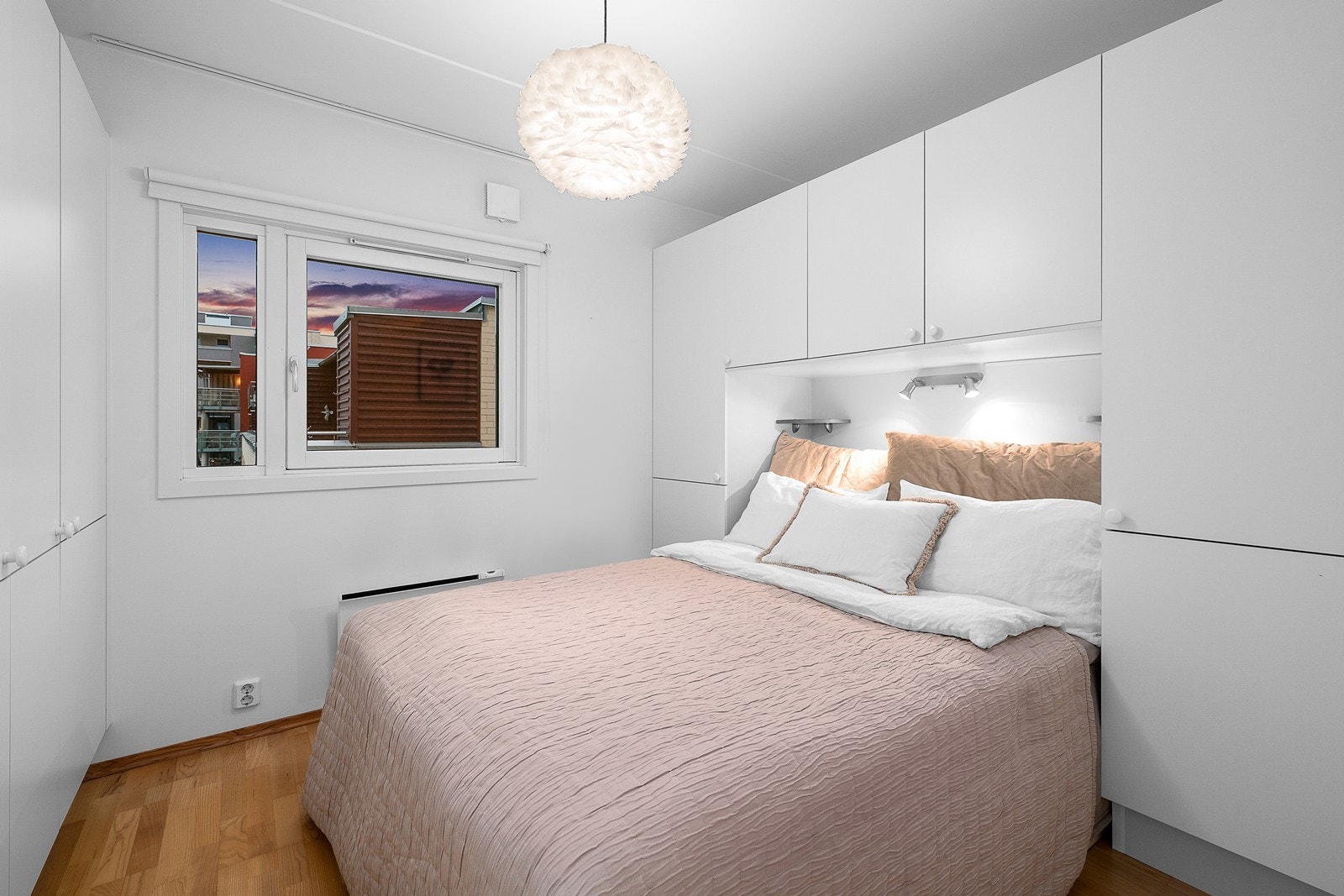 Romslig soverom med parkett på gulv, lyse farger og skreddersydd garderobeløsning. Galleribilde