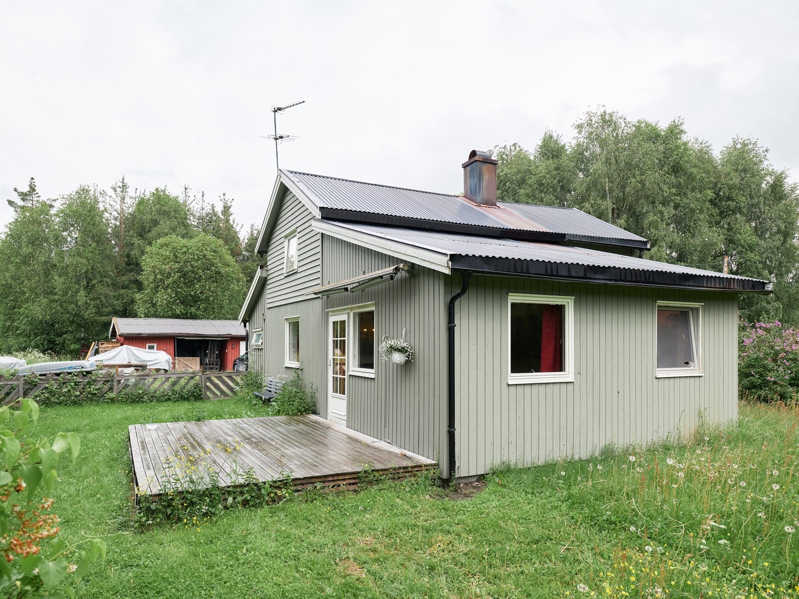 I bakgrunnen synes uthuset, med carport og flere boder. Galleribilde