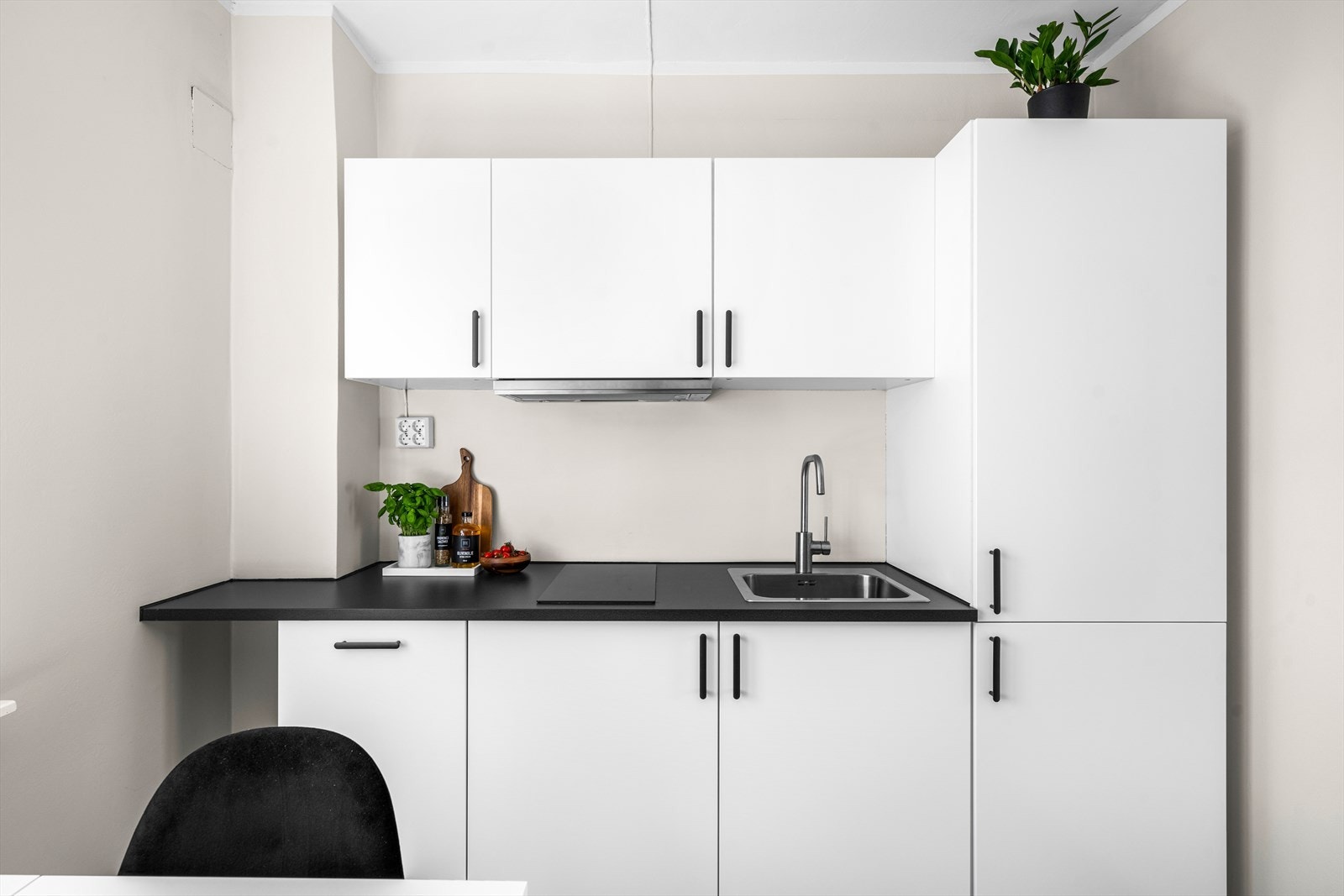 Moderne kjøkken med hvite skap og svart benkeplate. Galleribilde