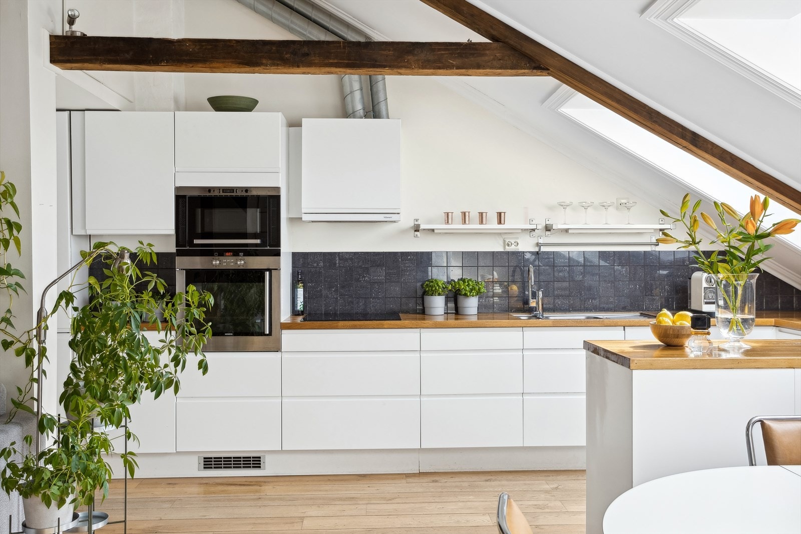 Kjøkkenet består av Ikea kjøkkeninnredning med slette lakkerte fronter, heltre eik benkeplate med fliser over, 1 ½ underlimt oppvaskkum med benkebeslag, kjøkkenventilator antatt med kanal ut, integrerte hvitevarer Galleribilde