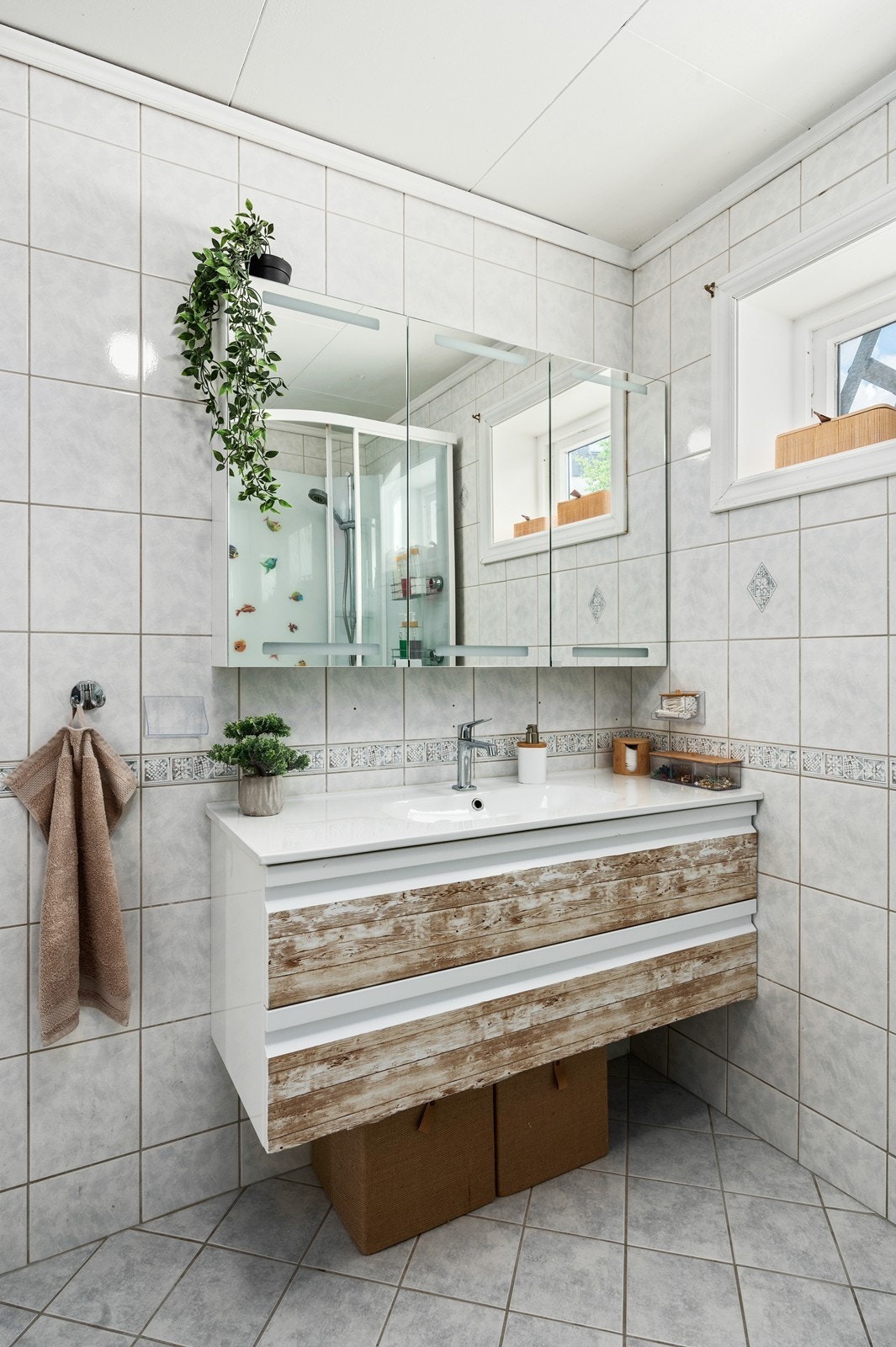 Baderomsinnredning med servant og skuffer under. Det er speilskap på veggen. Galleribilde