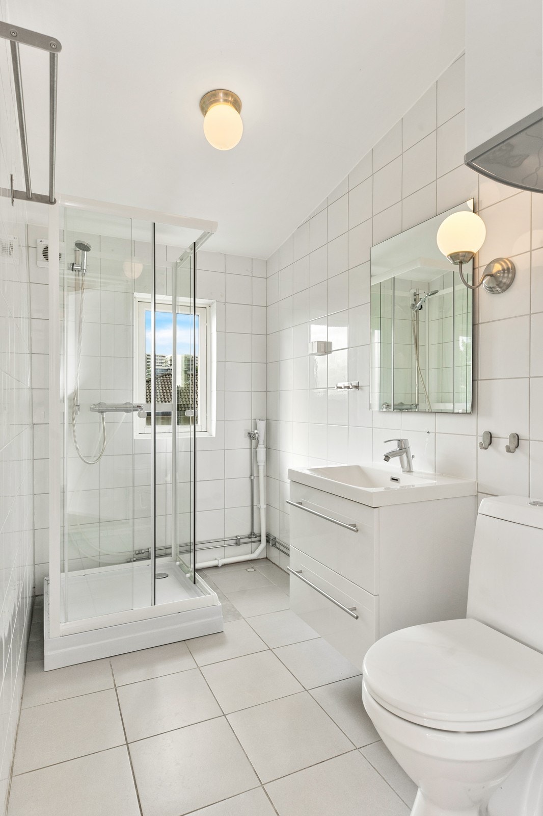 Badet er flislagt og er innredet med toalett, servant på innredning og dusj Galleribilde