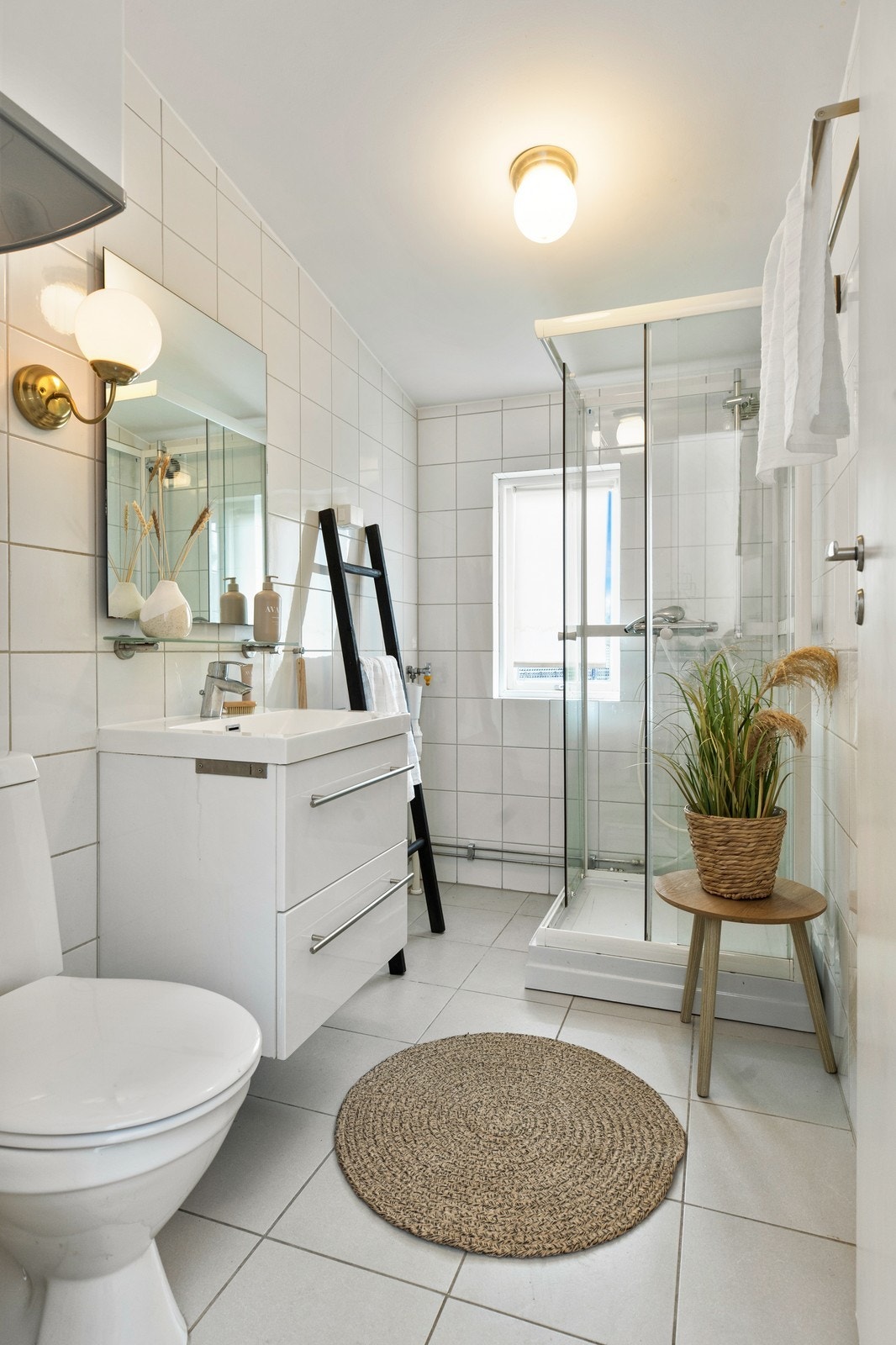 Badet er flislagt og er innredet med toalett, servant på innredning og dusj Galleribilde