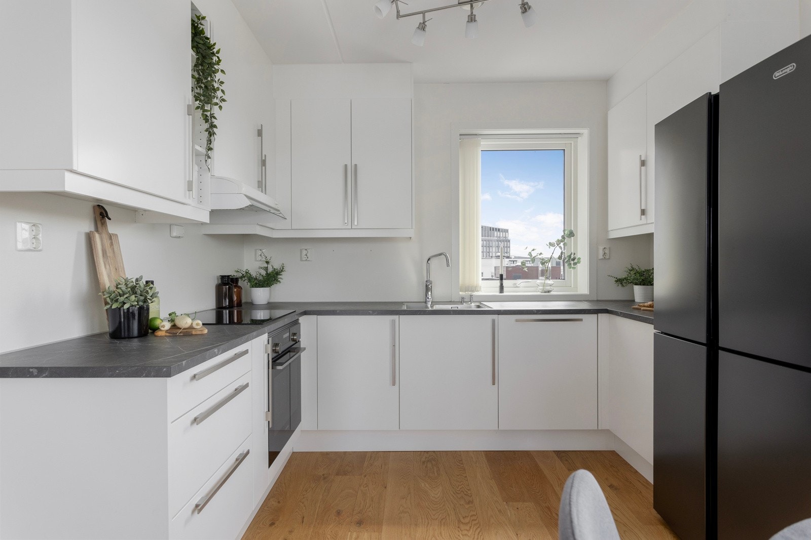 Romslig Sigdal kjøkken med vindu mot bakgård med morgensol. Galleribilde