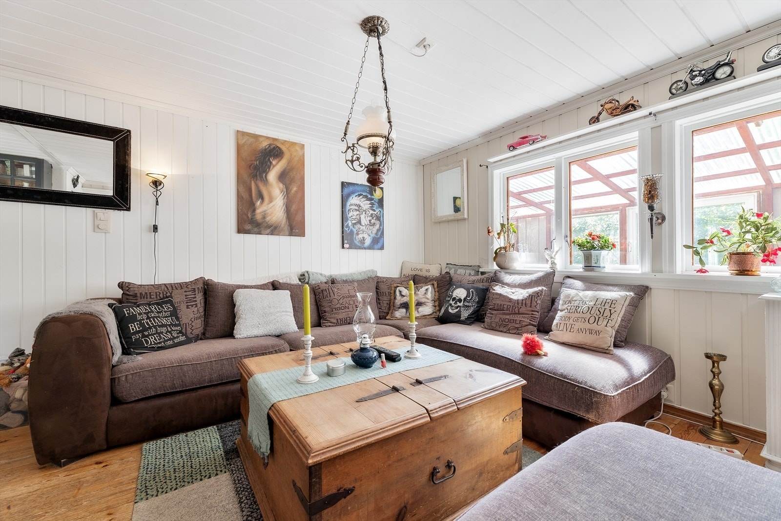 Stue med store vinduer og utsikt mot innglasset veranda. Galleribilde