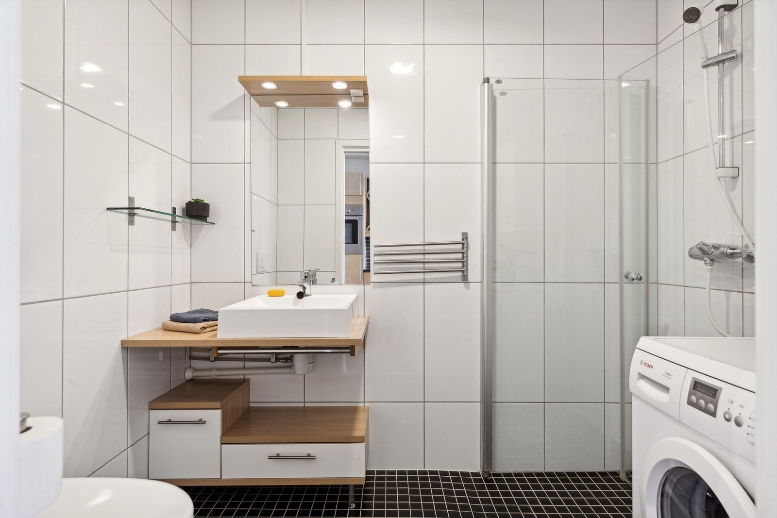 Flislagt baderom på 3,7 m² utstyrt med blant annet gulvvarme, innfellbare dusjvegger, opplegg for vaskemaskin og vegghengt klosett. Galleribilde