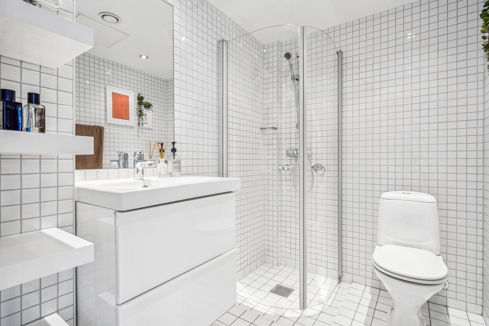 Badet er utstyrt med toalett, dusjhjørne med glassdører, baderomsinnredning med nedfelt servant og speil. Galleribilde