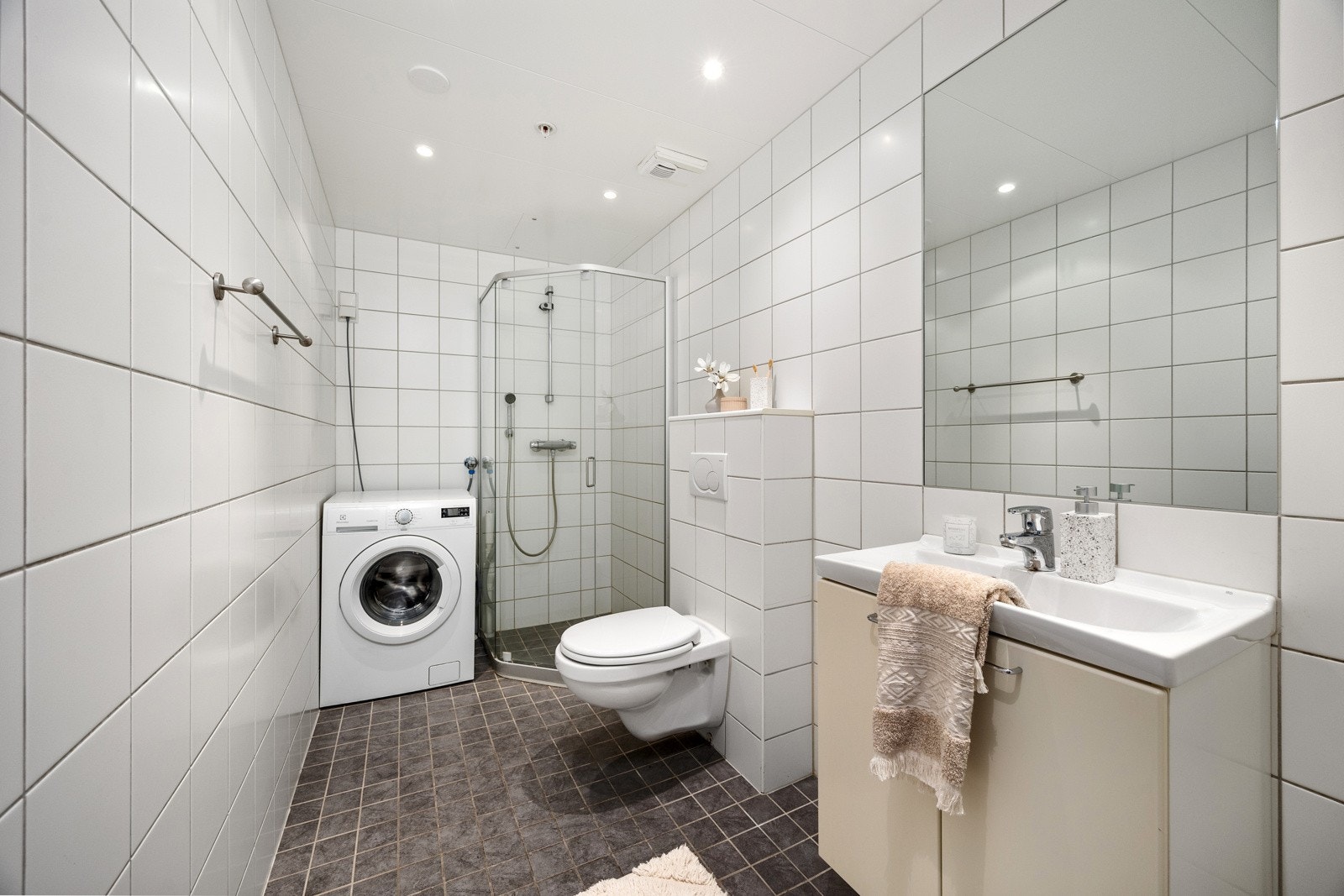 Badet er romslig og innredet med grå og hvite fliser, gulvvarme og downlights. Vaskemaskin medfølger handelen. Galleribilde