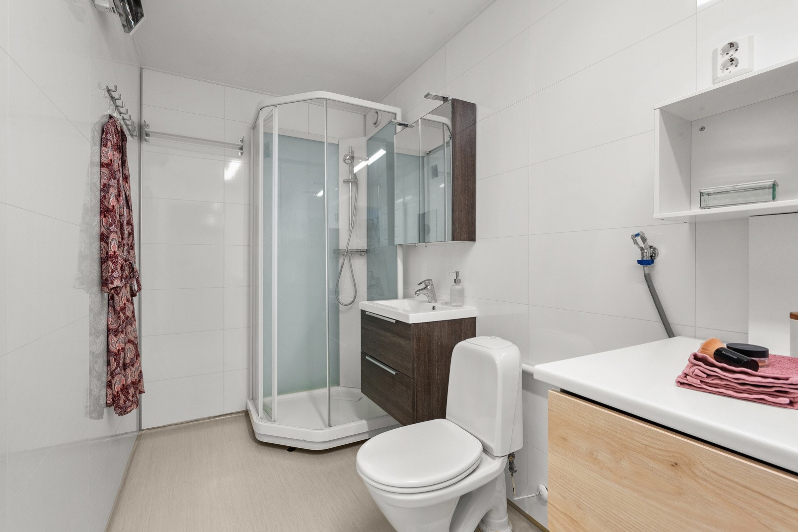 Badet har servantskap med glatte fronter og heldekkende servant, i tillegg til gulvmontert toalett. Speilskap med lysarmatur på vegg over servant gir ekstra lagringsmuligheter. Galleribilde