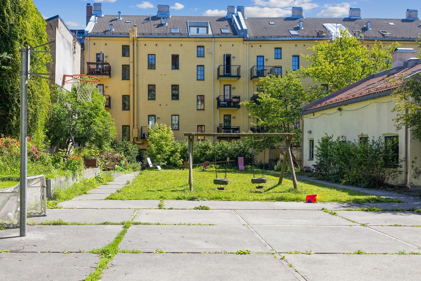 Bakgård med lekeplass, sitteplasser og basketbane Galleribilde