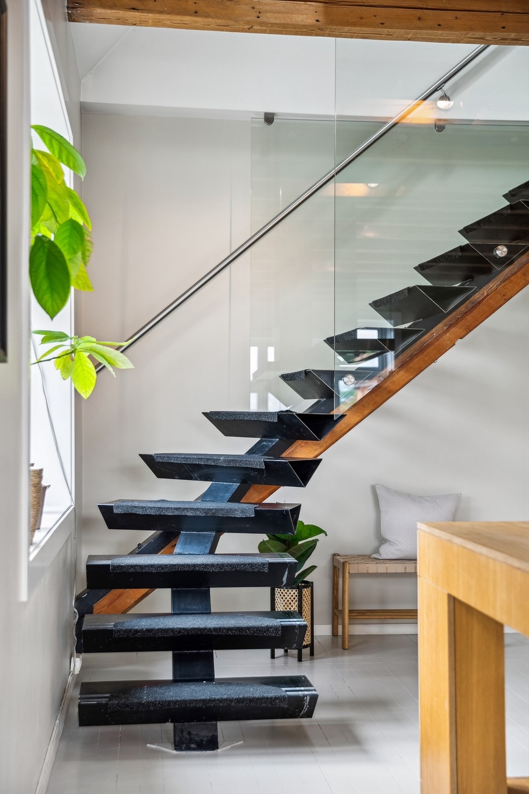Spesialdesignet, vinklet trapp i stål og med glass i rekkverk til loftsetasje. Den arkitekttegnede trappen er basert på en diagonal takbjelke og omtalt i interiørartikler. Galleribilde