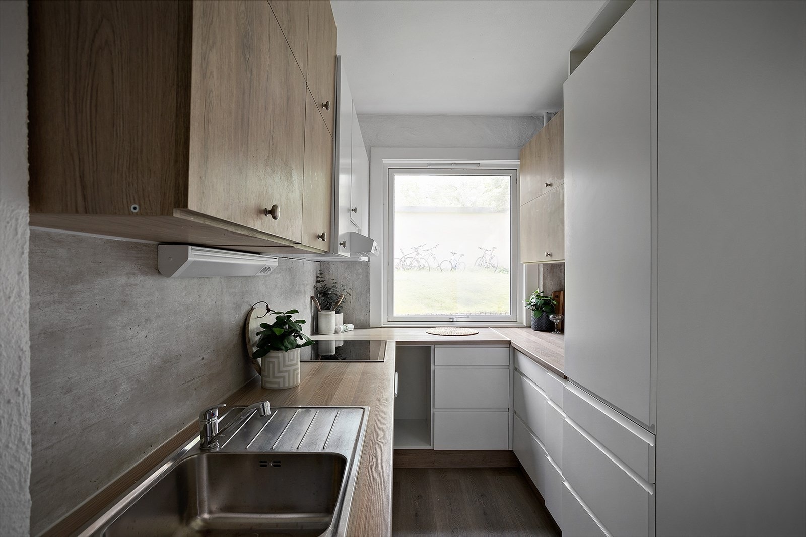 Kjøkkeninnredning med lyse slette fronter, benkeplater av laminat og nedfelt oppvaskkum med ett-greps armatur Galleribilde