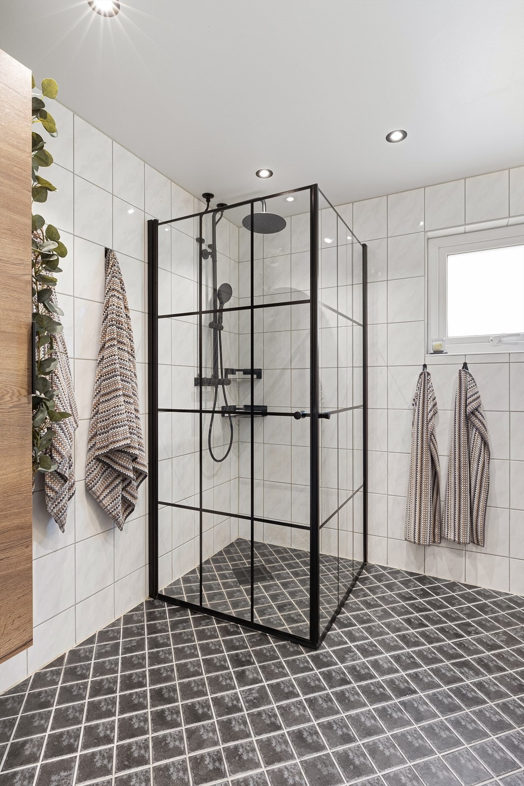 Dusjhjørne med innfellbare glassdører og fossefalldusj, samt vegghengt toalett og opplegg for vaskemaskin/tørketrommel. Galleribilde