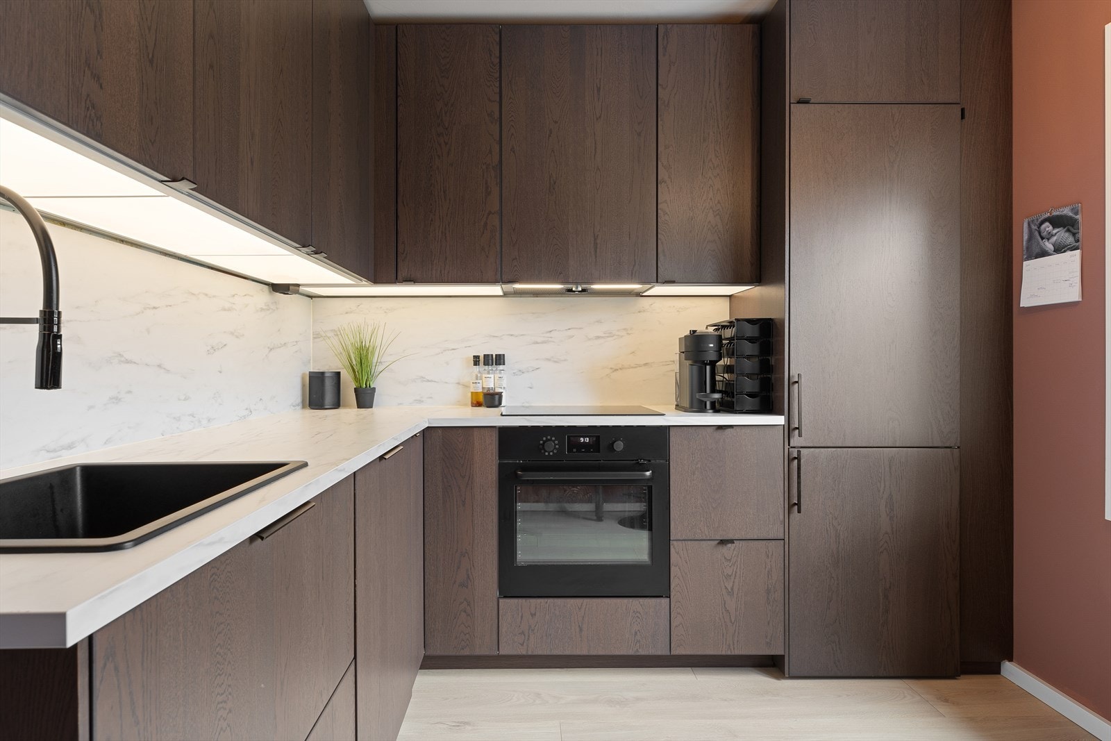 Innredningen er fra IKEA og har glatte fronter på over- og underskap. Laminat benkeplate med oppvaskkum. Integrerte hvitevarer i form av komfyr, induksjonplatetopp, oppvaskmaskin og kjøl/fryseskap. Galleribilde