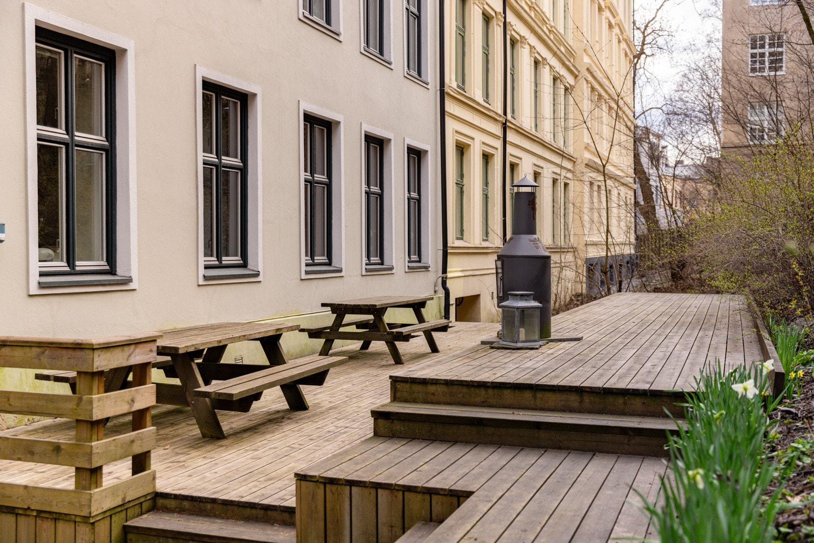 Pent indre gårdsrom med sittegrupper, platting, grill og beplantning. Bakgården ble renovert i 2022/2023. Galleribilde