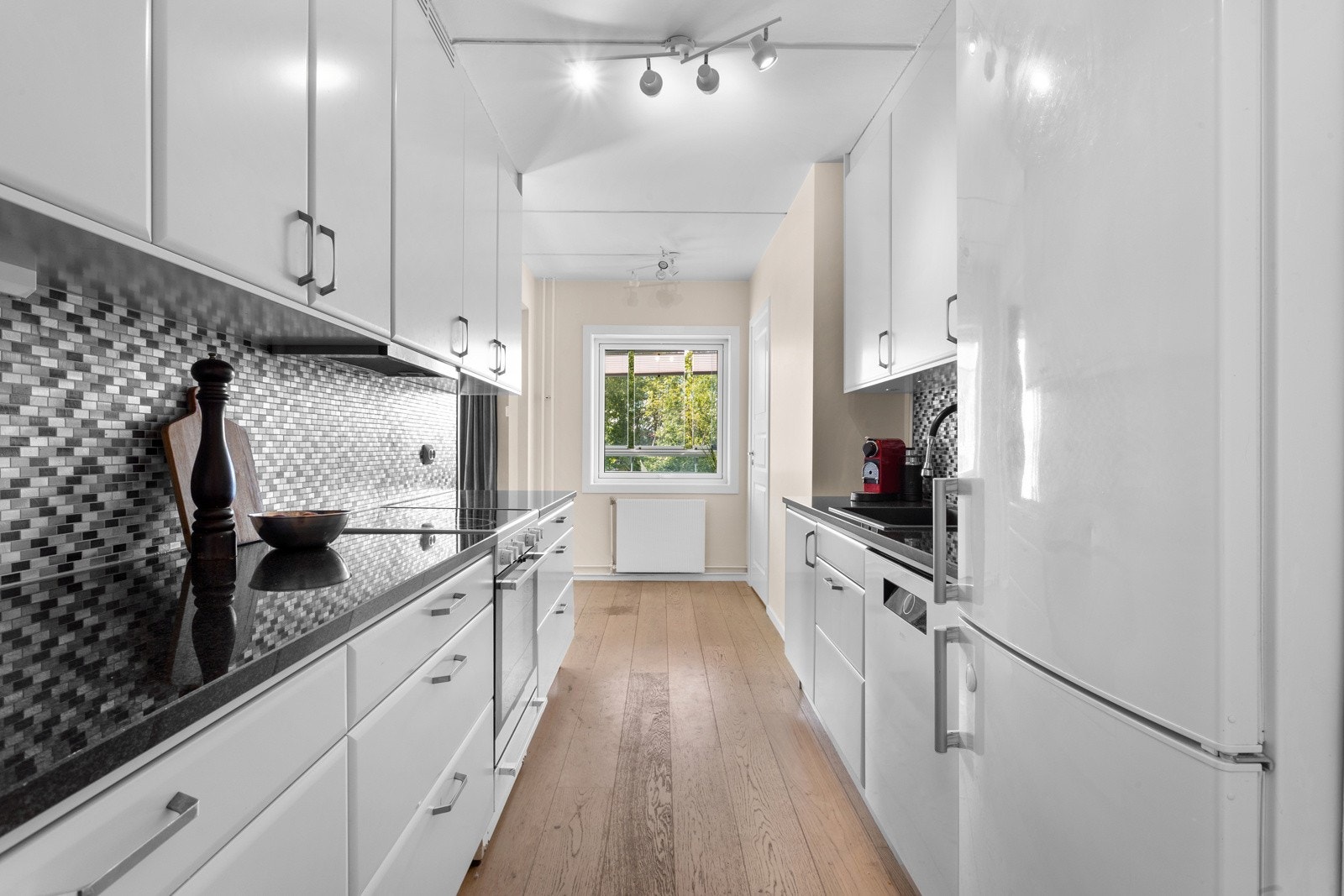 Kjøkkenet har glatte fronter og benkeplate i granitt Galleribilde